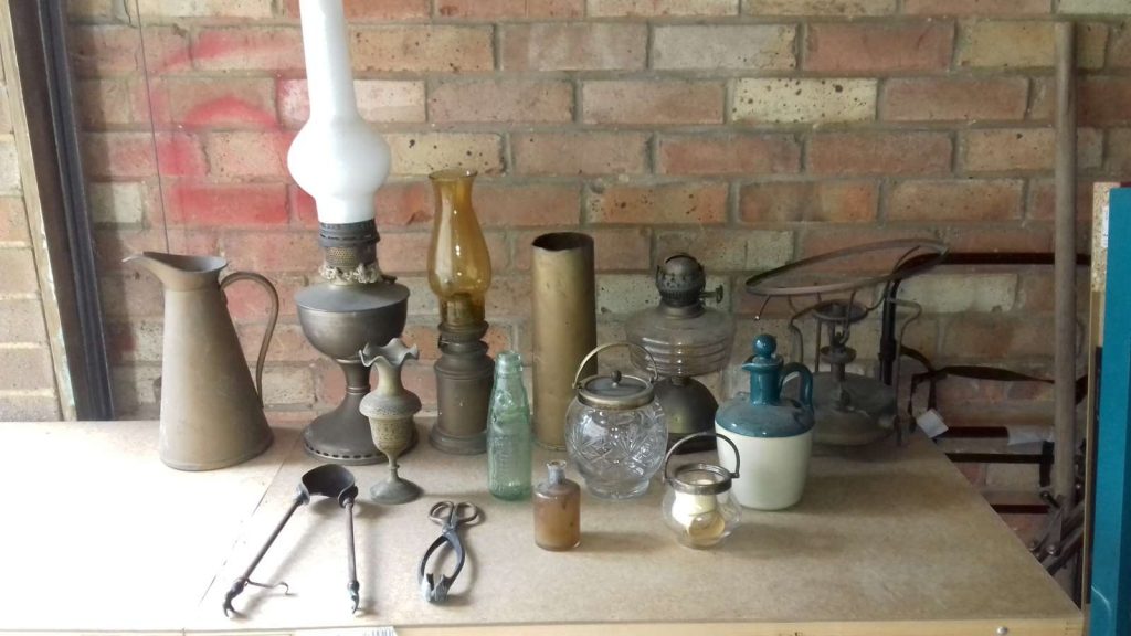 Collection of bottles, jars, oil lamps, jugs, tongs, Primus, shell case