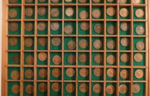 A collection of 70 plus British farthings in a display box - coins range from George 4th (1834), Queen Victoria through to Queen Elizabeth II and the last farthing issued in 1956