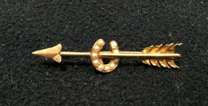 Seeded pearl horseshoe on a golden arrow brooch. Estimate £60-£80